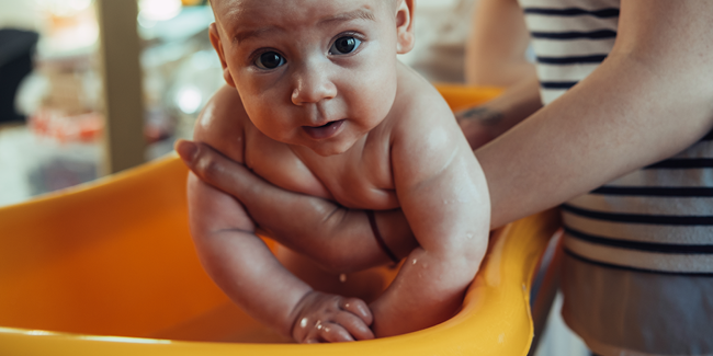 Photo of a baby receiving a bath.