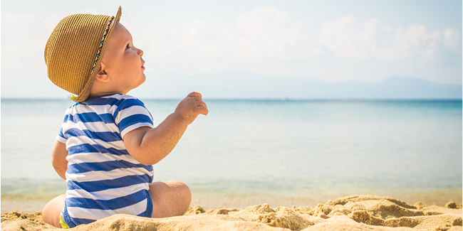 A cute baby in a hat on the beach