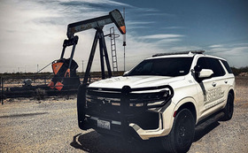 A police cruiser is parked near an oilfield pumpjack