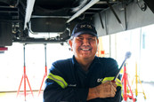 DCTA mechanic holding a wrench standing under a bus