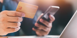 hand holding a credit card and using a computer