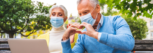 Senior couple with masks viewing laptop