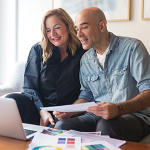 Couple in living room reviewing documents in front of laptop