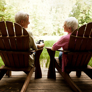 Senior couple sitting in chairs on a porch smiling at each other