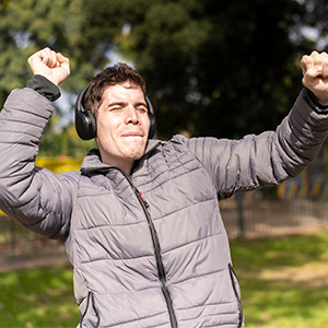 happy young man with headphones on dancing in a playground