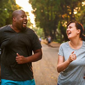 Man and a woman laughing while running together on a road