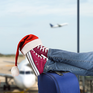 teen with suitcase in airport santa hat