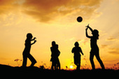 children playing with a ball at sunset