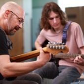 Two men playing guitars in the library