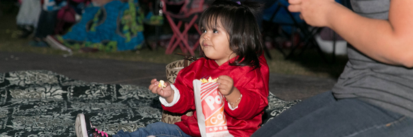 child eating popcorn during an outdoor movie