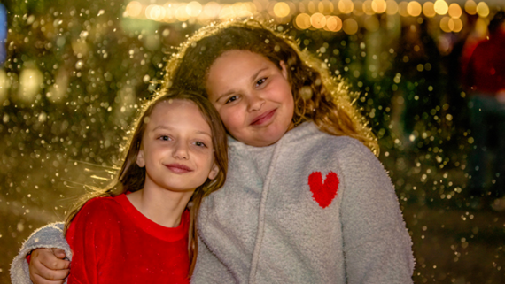 Two girls smiling under the snow falling