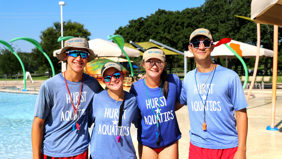 Photo of four Hurst Aquatics lifeguards smiling at Chisholm Aquatics Center