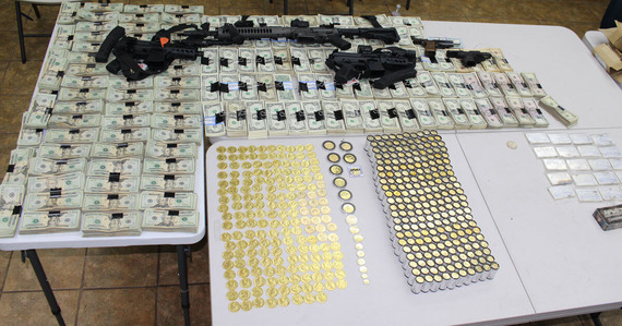 table with contraband seized including cash and guns