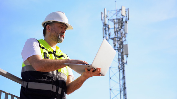 A communications tower worker electronically programs the tower.