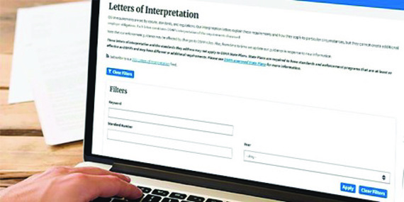 A man's hand is on a computer keyboard with a "Letter of Interpretation" website open on his monitor.