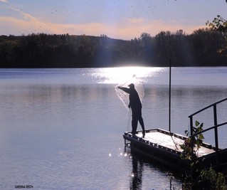 Fisherman standing on dock throwing a casting net