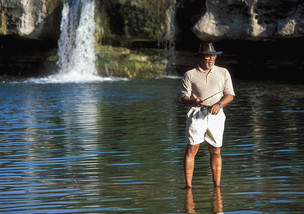 man fishing in front of waterfall