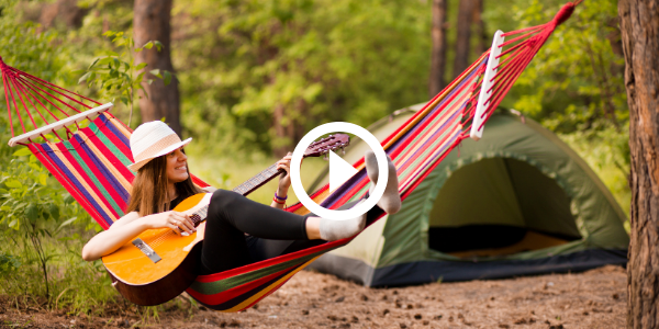 girl playing guitar in hammock by tent, video link