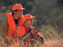 man and boy in blaze orange waiting to take a shot