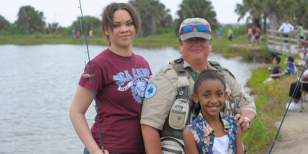 A TPWD volunteer with two girls fishing