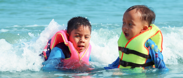 2 boys in life jackets splashing in water