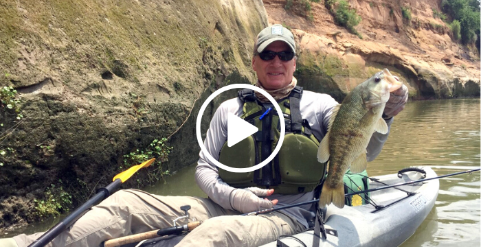 angler in kayak holding Guadalupe bass, with video link