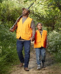 Father and daughter in orange vests walk while hunting squirrels