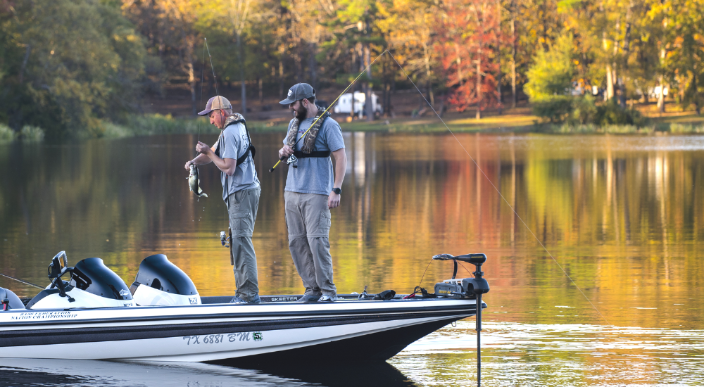 two anglers in boat, fall color in background