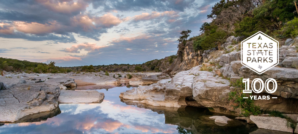 Pedernales Falls SP at sunrise with 100 Years of State Parks logo