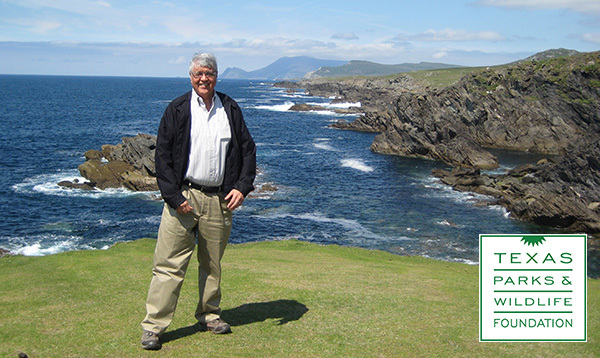 A man standing on a cliff overlooking a coastline.