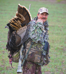 Hunter carrying turkey harvest on his back