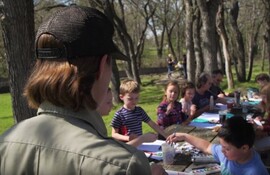 Children creating art at a long table outside