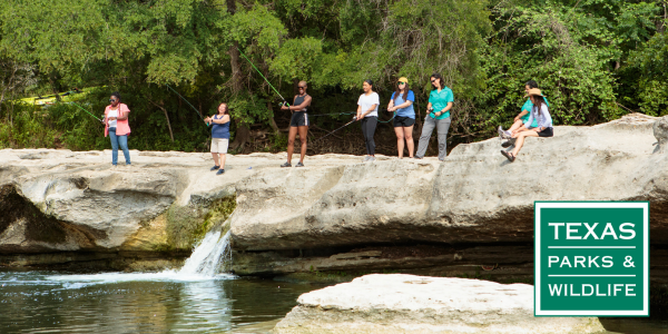 Image of a group of women fishing from a rock ledge over a waterfall.