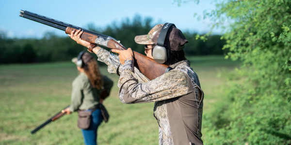 Image of a woman aiming a shotgun during a dove hunt.