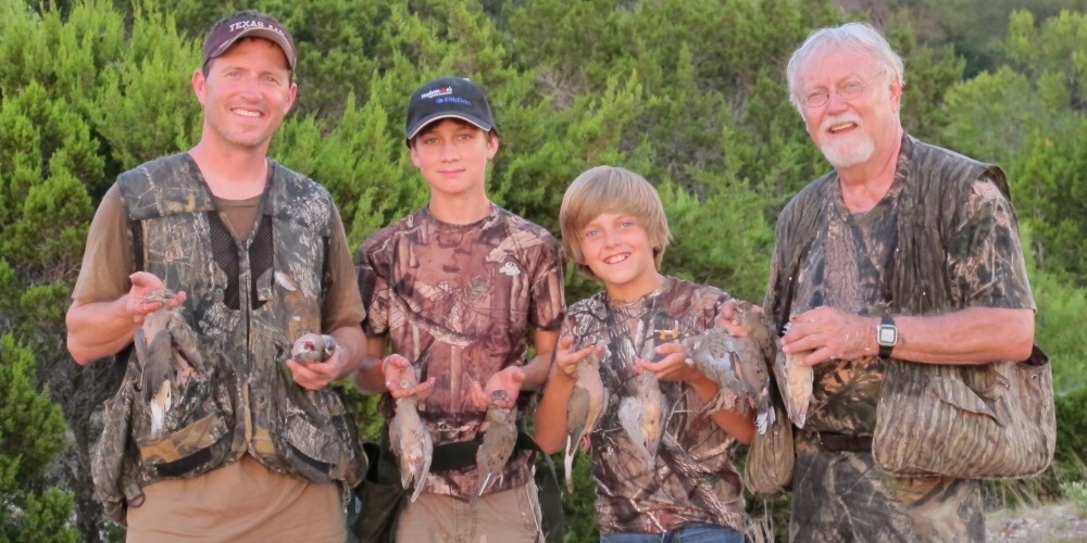 Two adult men and two boys all holding dove harvests