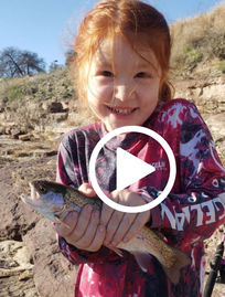 Young girl with big smile holding a rainbow trout, video link