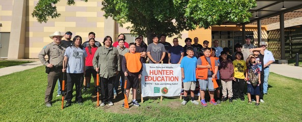 Students and game warden pose for class pic outside of school