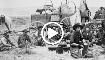 Vintage black and white image of cowboys using Dutch ovens, video link