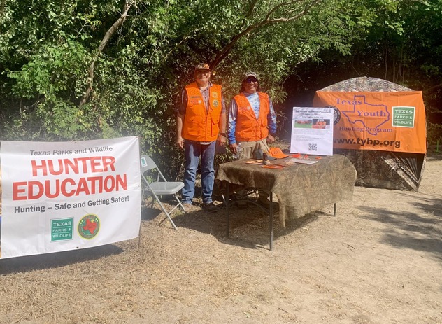 two Hunter Ed instructors pose next to educational display
