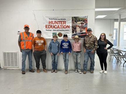 Students pose with instructor in school hallway