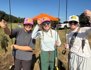 Picture of girls with fish on their fly rods.