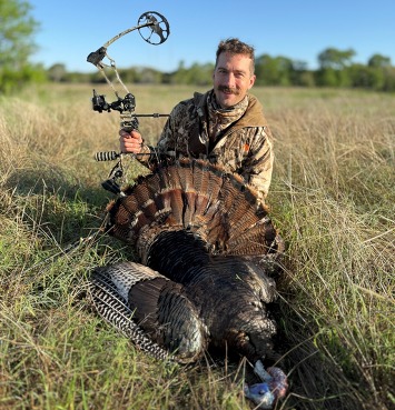 Bowhunter posing with harvested turkey