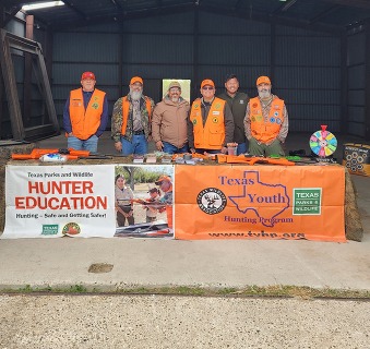 Hunter Ed instructors pose in front of banner