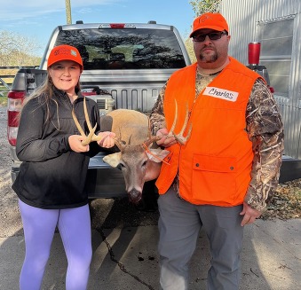 Girl poses with hunting guide and the deer she harvested on the back of a truck