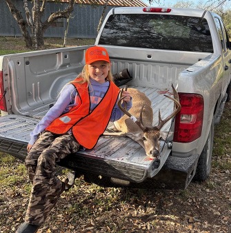 Girl poses on truck tailgate with deer harvest