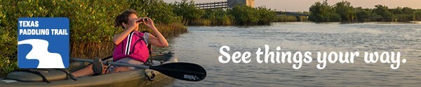 Paddler looking at wildlife through binoculars, link to paddling trails website