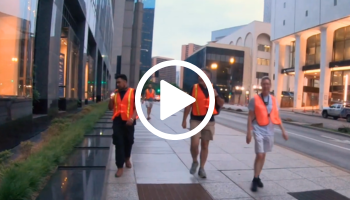 3 people in orange vests search for birds in city, video