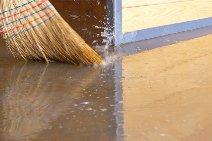 Broom sweeping away standing water on a floor