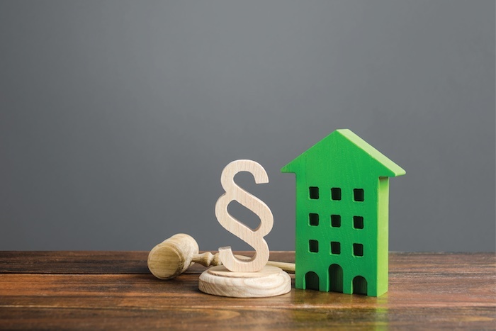 A wooden toy house with a wooden statute symbol