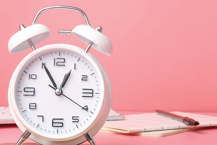 White alarm clock on pink background